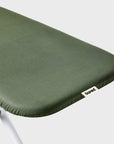 Close-up of an olive green ironing board cover rear section with a small white 'bored' brand tag.