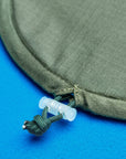 Close-up of an olive green ironing board cover nylon tesnioning cord, featuring a small translucent plastic toggle.